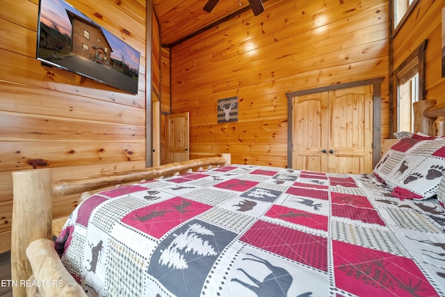 bedroom featuring ceiling fan, a high ceiling, and wooden walls