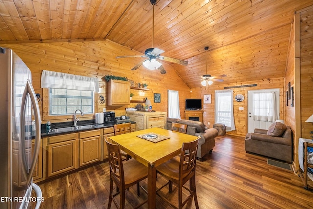 dining space featuring sink, dark hardwood / wood-style floors, vaulted ceiling, wooden walls, and wood ceiling