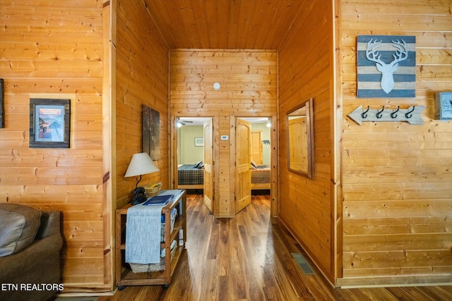 hallway featuring dark hardwood / wood-style flooring, wooden ceiling, and wooden walls