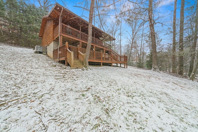 snow covered rear of property with a wooden deck