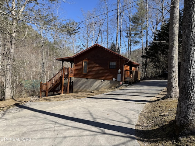 view of home's exterior featuring concrete driveway, crawl space, and faux log siding