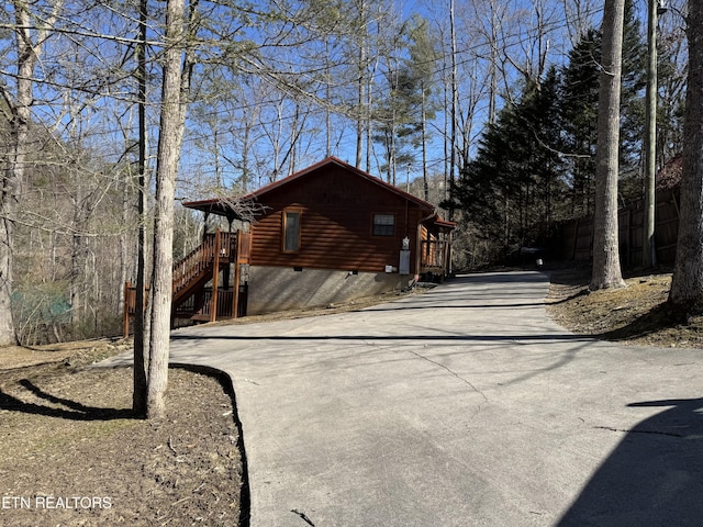 view of side of home featuring concrete driveway and crawl space