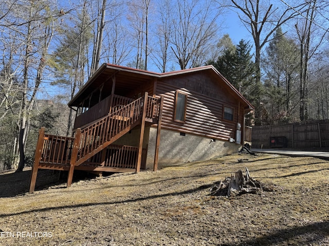 view of property exterior featuring crawl space, fence, stairway, and a wooden deck