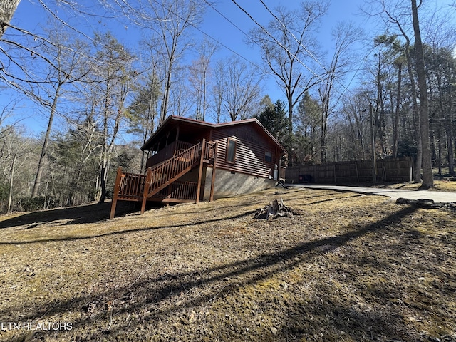 view of home's exterior featuring stairs, a wooden deck, and fence