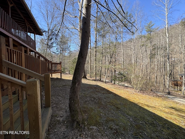 view of yard with a deck and a wooded view