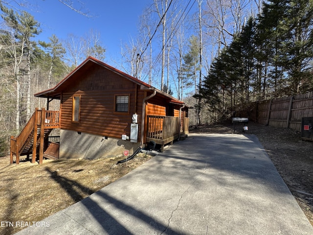 view of side of property with log veneer siding, fence, and driveway