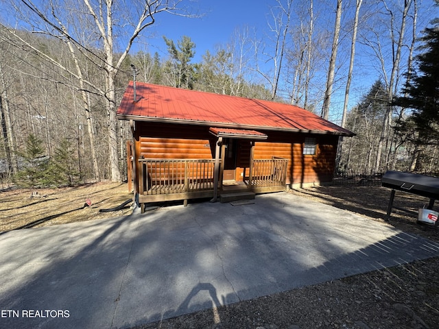 view of front of home featuring a porch, faux log siding, and metal roof