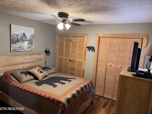 bedroom featuring a textured ceiling, two closets, dark wood finished floors, and a ceiling fan