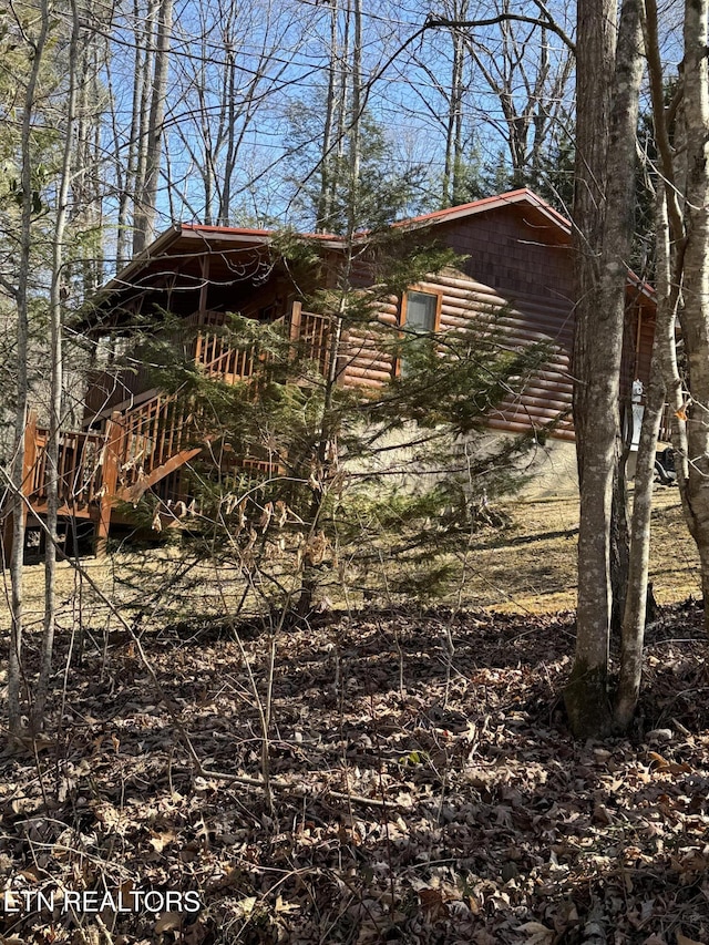 view of property exterior featuring stairs and log veneer siding