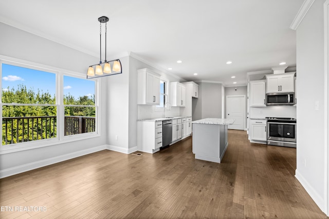 kitchen featuring pendant lighting, white cabinets, decorative backsplash, a kitchen island, and stainless steel appliances