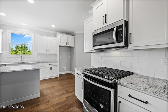 kitchen with white cabinetry, sink, light stone countertops, dark hardwood / wood-style floors, and appliances with stainless steel finishes