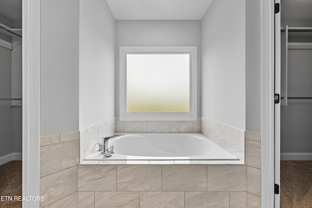 bathroom with a relaxing tiled tub and a healthy amount of sunlight