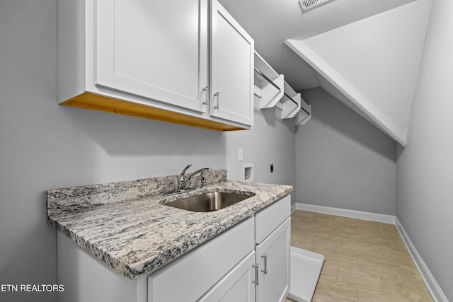 kitchen with light stone countertops, sink, and white cabinets