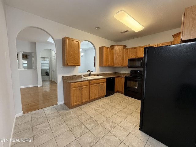 kitchen with sink, light tile patterned floors, and black appliances