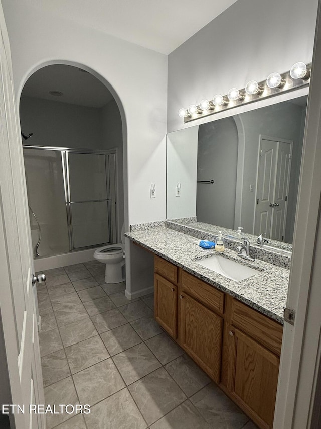 bathroom with tile patterned flooring, vanity, toilet, and a shower with shower door