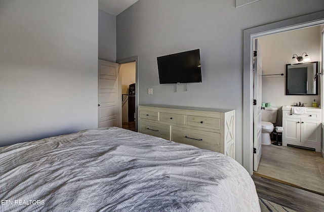 bedroom featuring ensuite bath, dark hardwood / wood-style flooring, and a towering ceiling