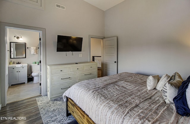 bedroom with dark hardwood / wood-style flooring, a high ceiling, and ensuite bath