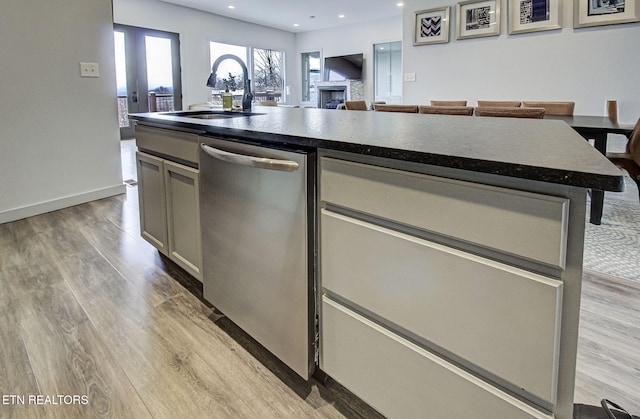 kitchen with light wood-type flooring, gray cabinetry, sink, dishwasher, and a kitchen island