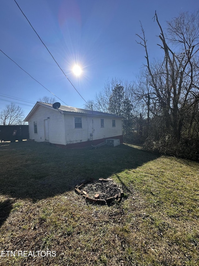 rear view of house featuring a fire pit and a lawn