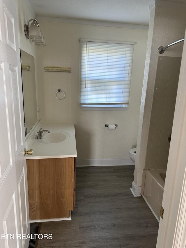 full bathroom with hardwood / wood-style floors, vanity, bathtub / shower combination, crown molding, and toilet