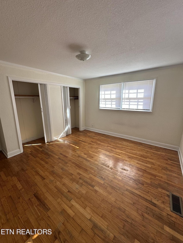 unfurnished bedroom featuring dark hardwood / wood-style flooring and a textured ceiling