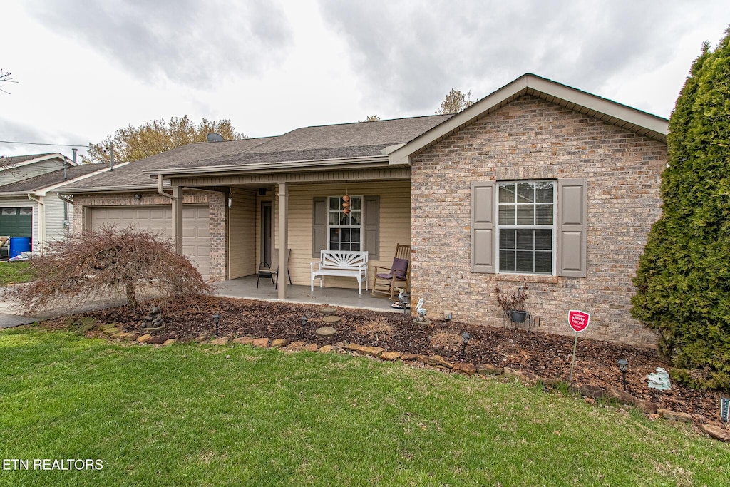 ranch-style house featuring covered porch, a garage, and a front lawn