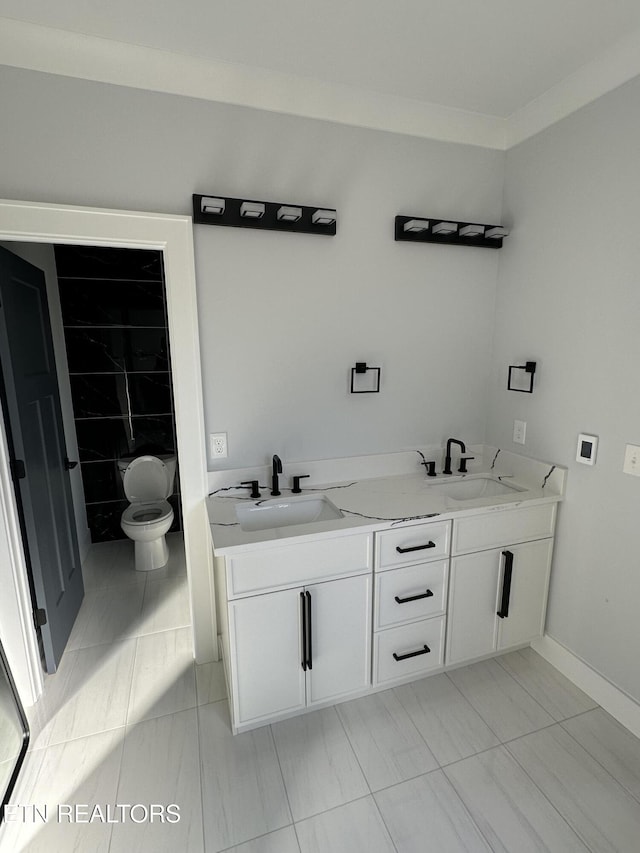 bathroom with toilet, vanity, and ornamental molding