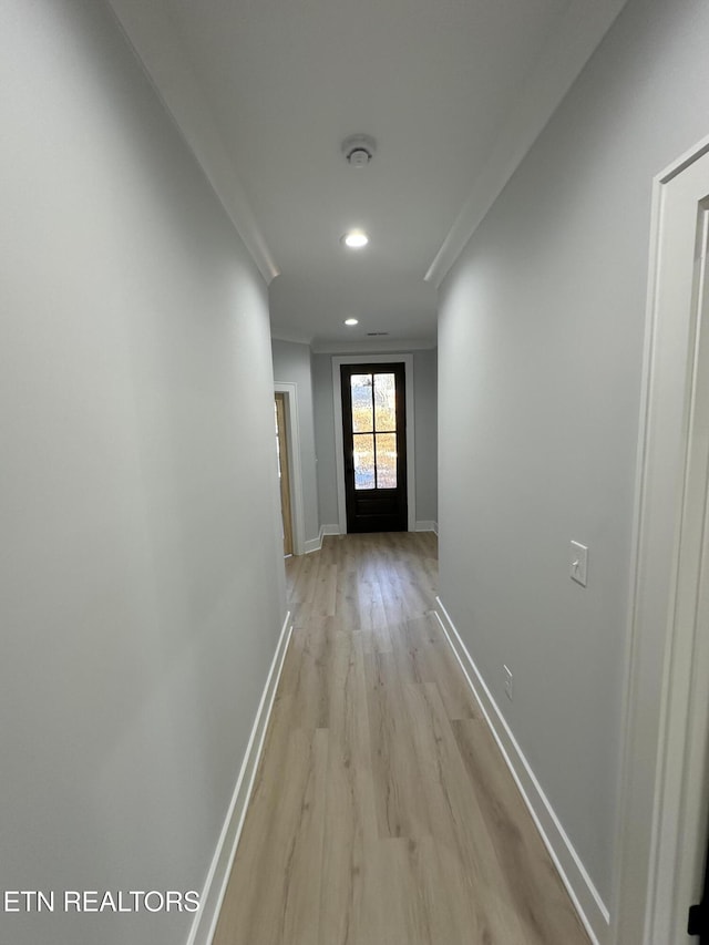 hall with light wood-type flooring and ornamental molding