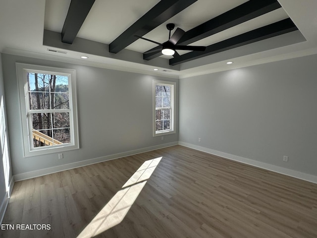 spare room with wood-type flooring, a healthy amount of sunlight, beamed ceiling, and ceiling fan