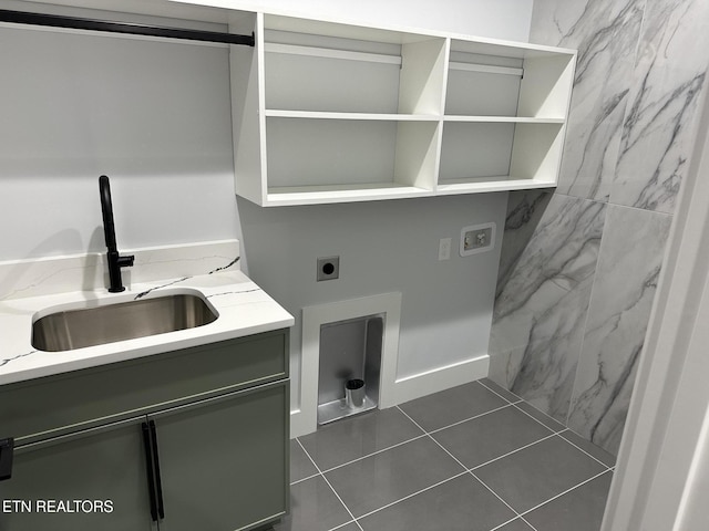 washroom featuring sink, electric dryer hookup, cabinets, and dark tile patterned flooring