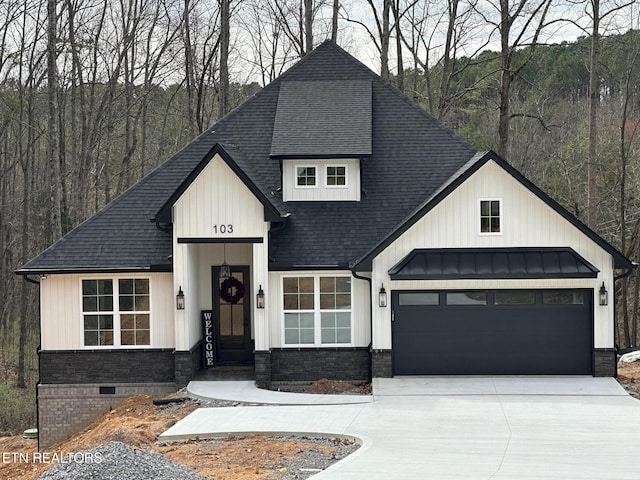 modern farmhouse style home with driveway, roof with shingles, stone siding, a view of trees, and board and batten siding