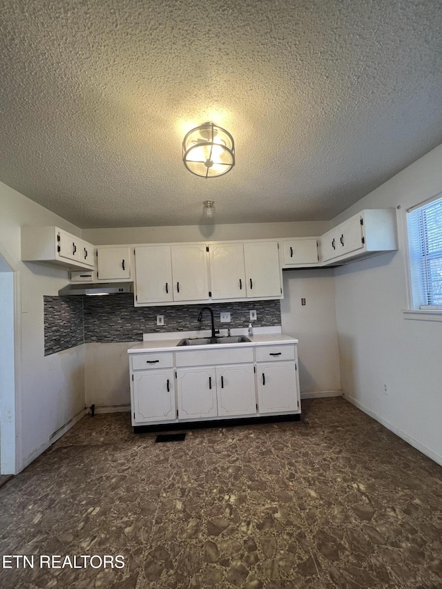 kitchen featuring backsplash, a sink, white cabinetry, and under cabinet range hood