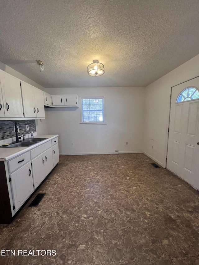 kitchen with light countertops, a sink, visible vents, and white cabinetry