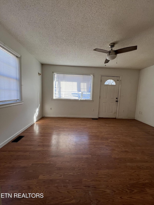 entrance foyer featuring visible vents, baseboards, dark wood-style floors, ceiling fan, and a textured ceiling