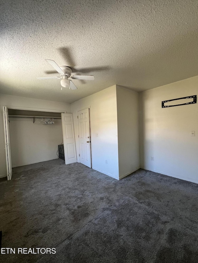 unfurnished bedroom with ceiling fan, a textured ceiling, and dark carpet