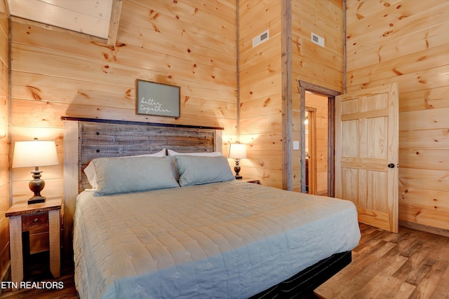 bedroom featuring hardwood / wood-style flooring and wooden walls