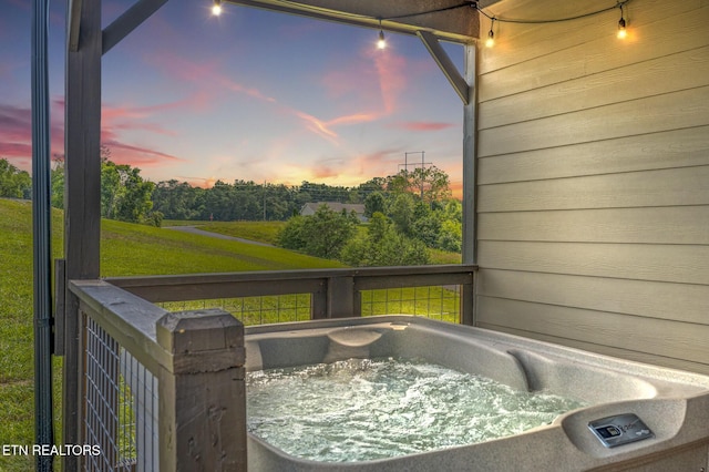 deck at dusk featuring a hot tub