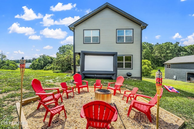 back of house with a fire pit and a yard