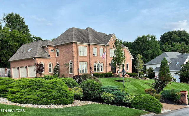 view of front of home with brick siding, a front lawn, a garage, and a shingled roof