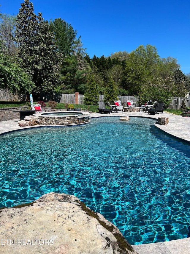 view of pool featuring a patio area and an in ground hot tub