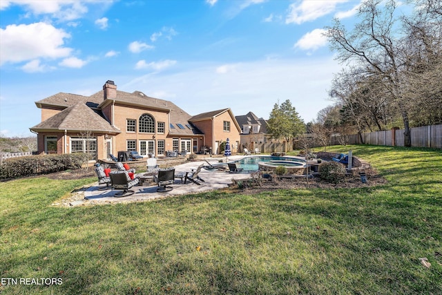 rear view of house featuring a fenced in pool, a chimney, a fenced backyard, a yard, and a patio area