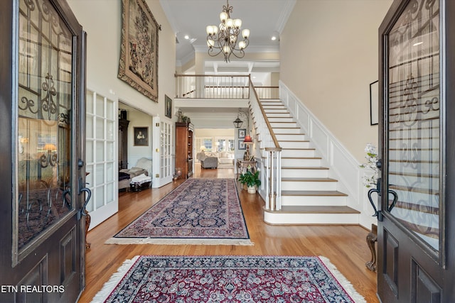 entryway featuring crown molding, stairway, french doors, wood finished floors, and a notable chandelier