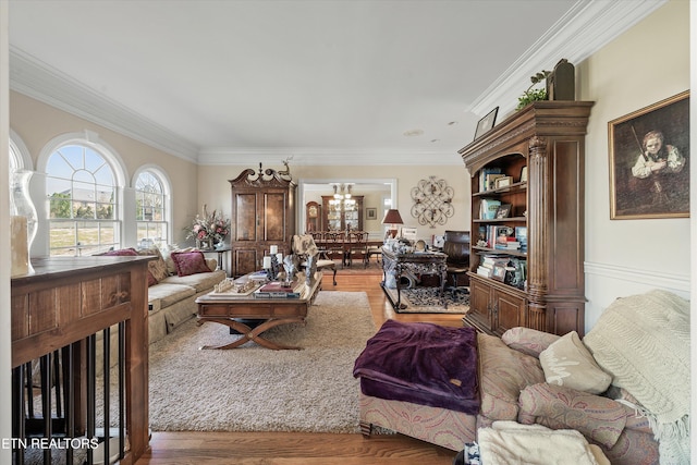 living area with an inviting chandelier, crown molding, and wood finished floors