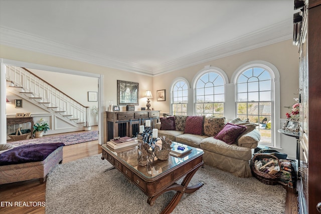 living room featuring a wealth of natural light, ornamental molding, stairs, and wood finished floors