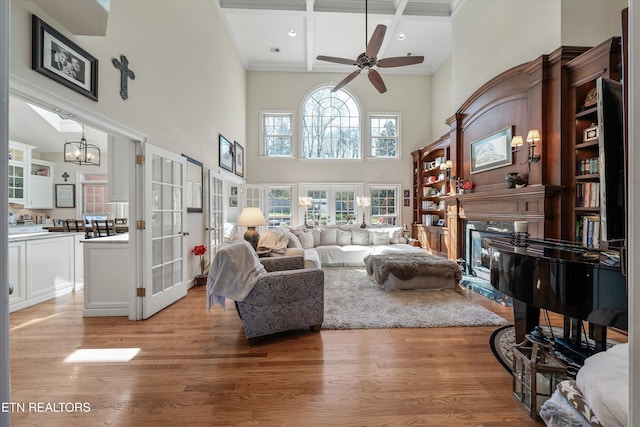 living area featuring french doors, coffered ceiling, a fireplace, and light wood finished floors