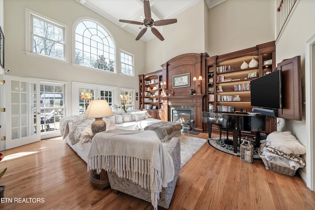 bedroom with a fireplace with flush hearth, french doors, a high ceiling, and wood finished floors