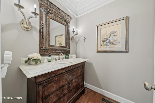 bathroom featuring vanity, wood finished floors, visible vents, baseboards, and ornamental molding