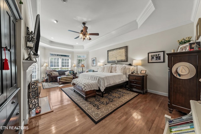 bedroom featuring a tray ceiling, baseboards, ornamental molding, and hardwood / wood-style flooring