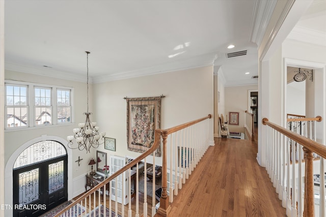 hall featuring wood finished floors, visible vents, french doors, a notable chandelier, and an upstairs landing