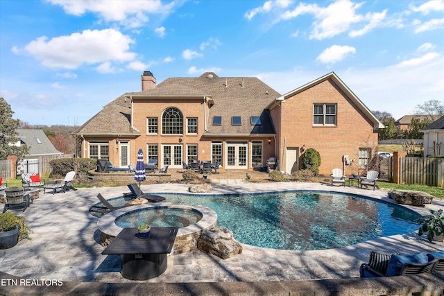 view of pool with a patio, fence, a pool with connected hot tub, french doors, and a fire pit